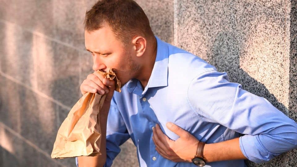 man breathing into paper bag