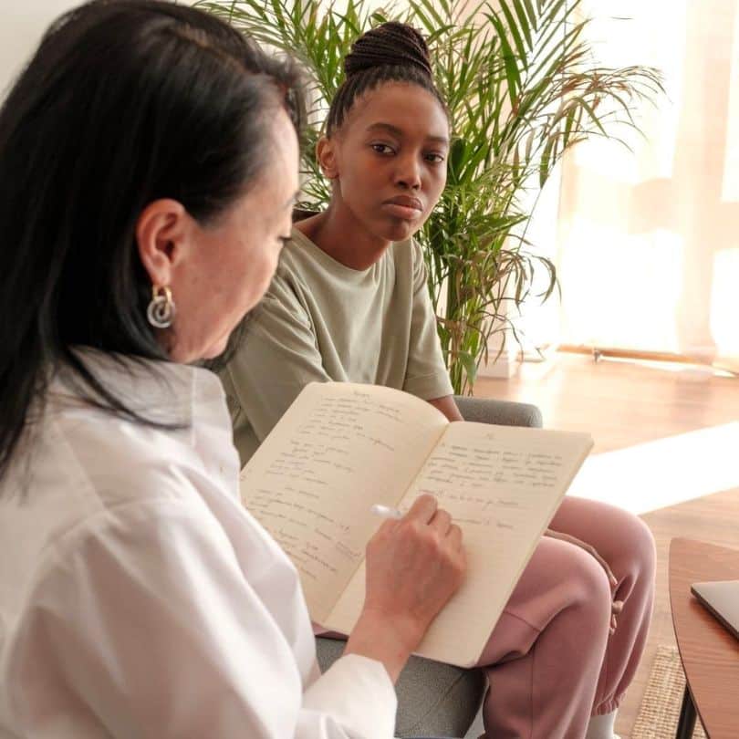therapist taking notes while talking to patient